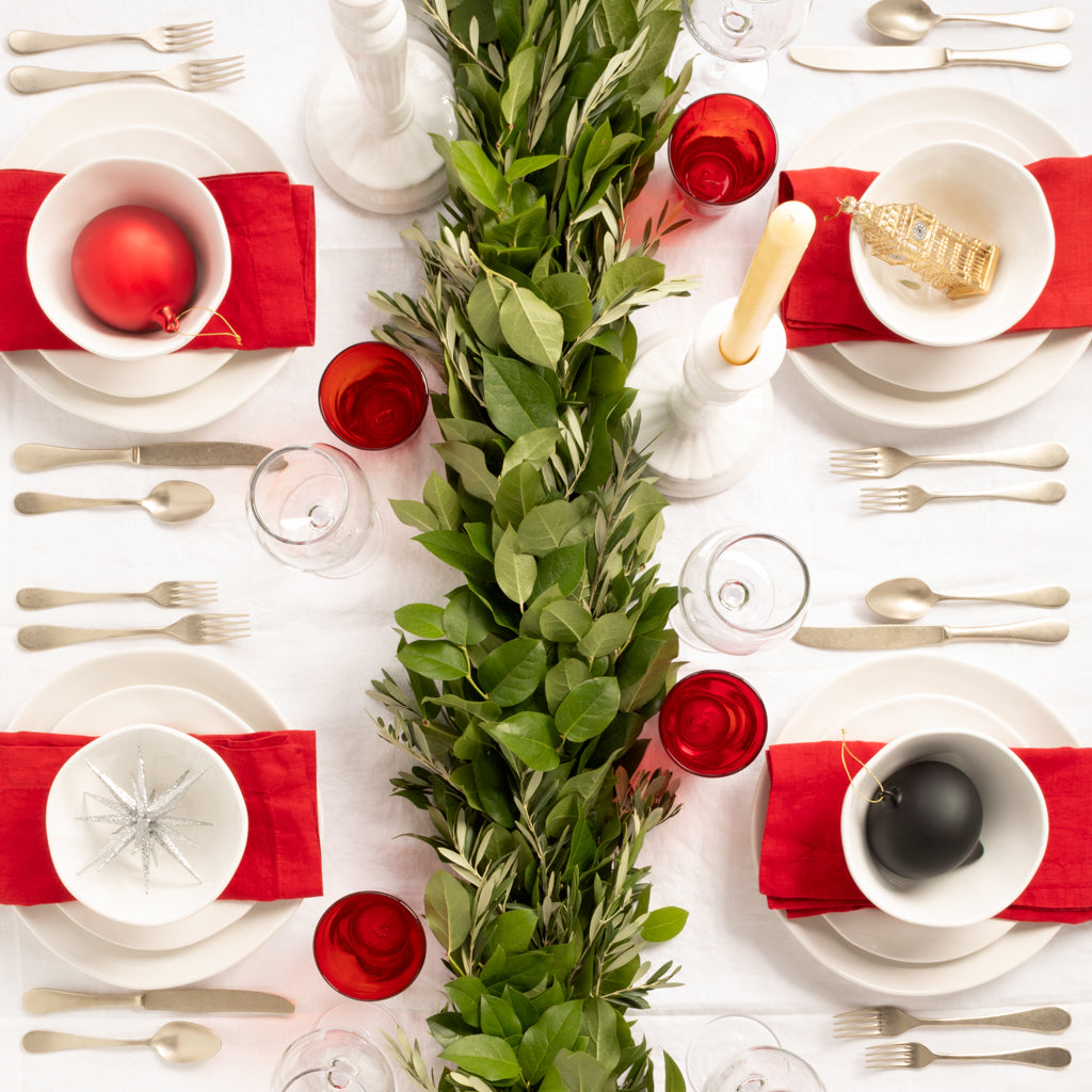 Vintage Champagne 5-piece flatware set on a festive white table with red napkins, green garland, and ornaments.