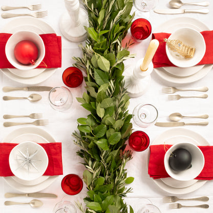 Vintage Champagne 5-piece flatware set on a festive white table with red napkins, green garland, and ornaments.