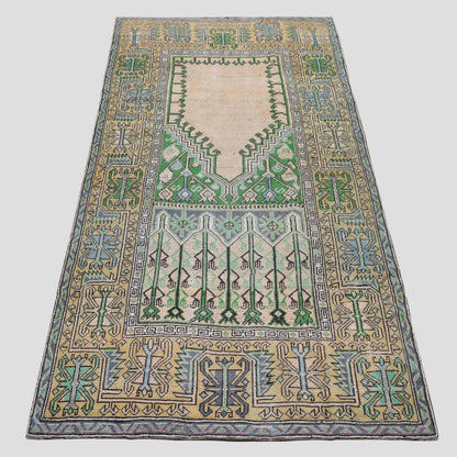 Vintage 4'7"x9' Turkish wool rug with cream base, green, blue, and yellow geometric patterns.