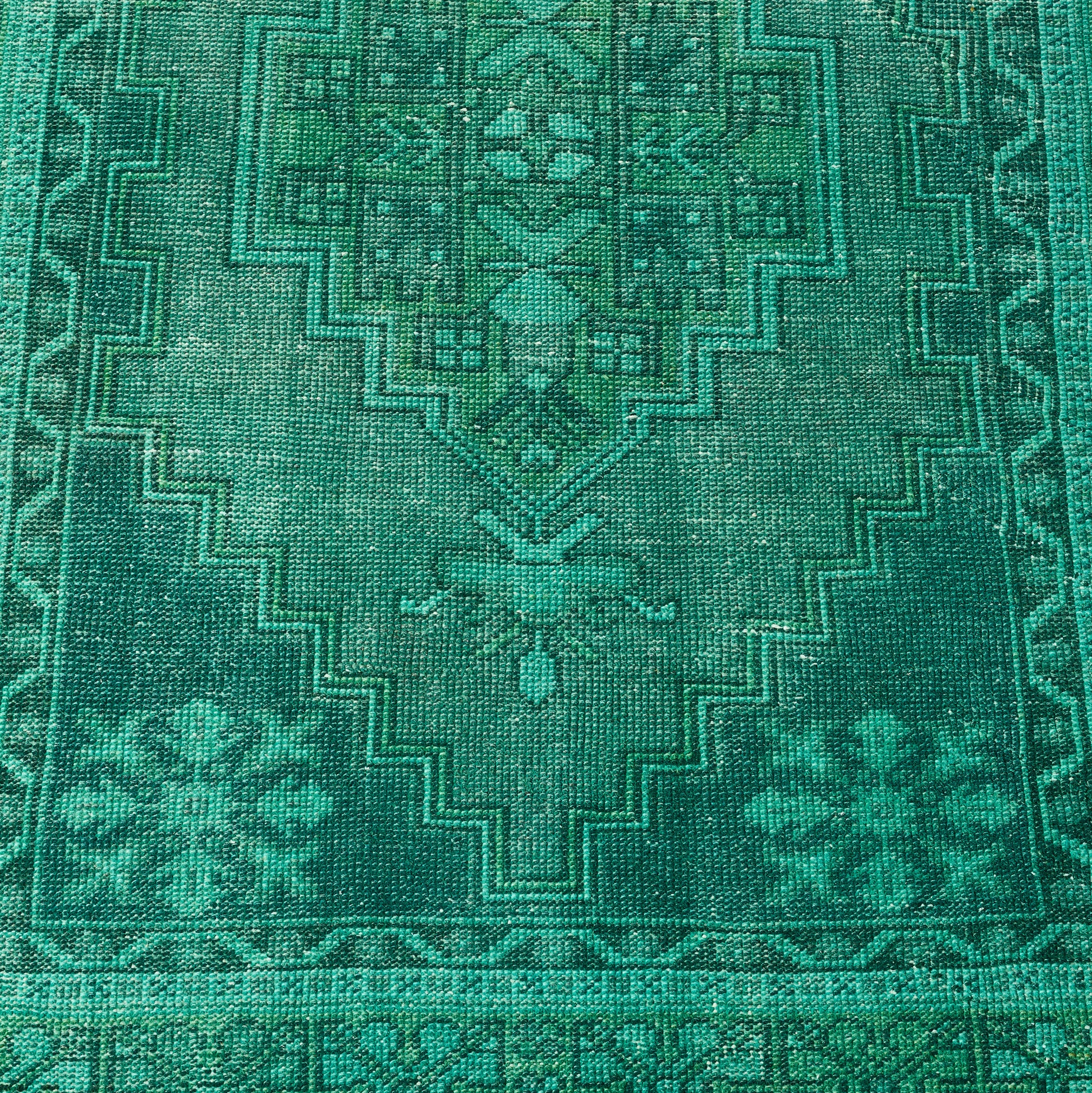Vintage green wool rug with a faded geometric pattern and low-pile, handcrafted Turkish design.