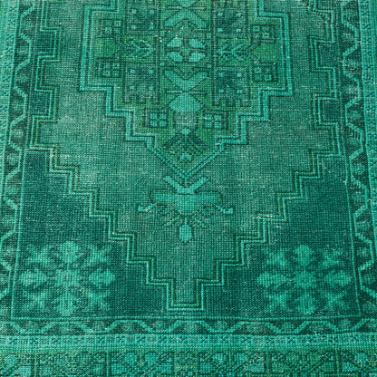 Vintage green wool rug with a faded geometric pattern and low-pile, handcrafted Turkish design.