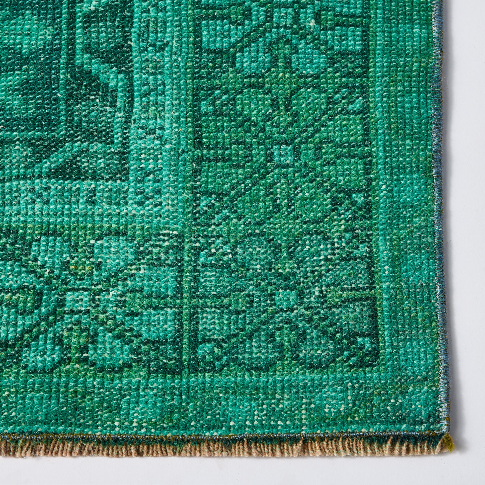 Vintage green wool rug with low-pile texture, faded geometric pattern, and hand-finished edges.