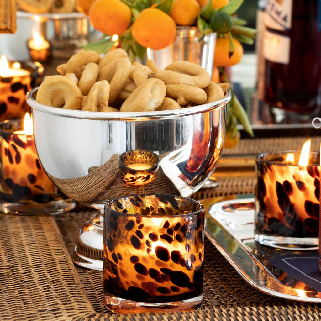 Vintage silverplate 6'' footed bowl filled with snacks, surrounded by leopard print votives and oranges.