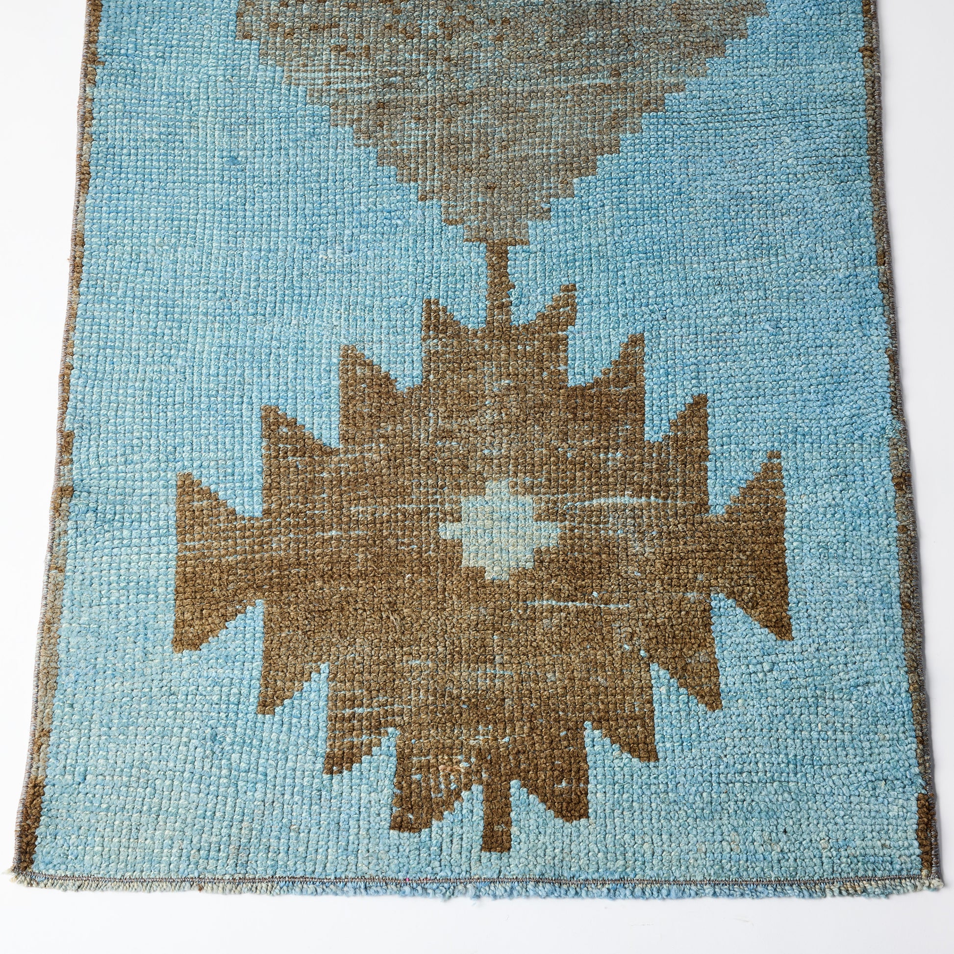 Vintage wool runner rug in light blue and brown with a handcrafted Aztec geometric pattern and distressed texture.