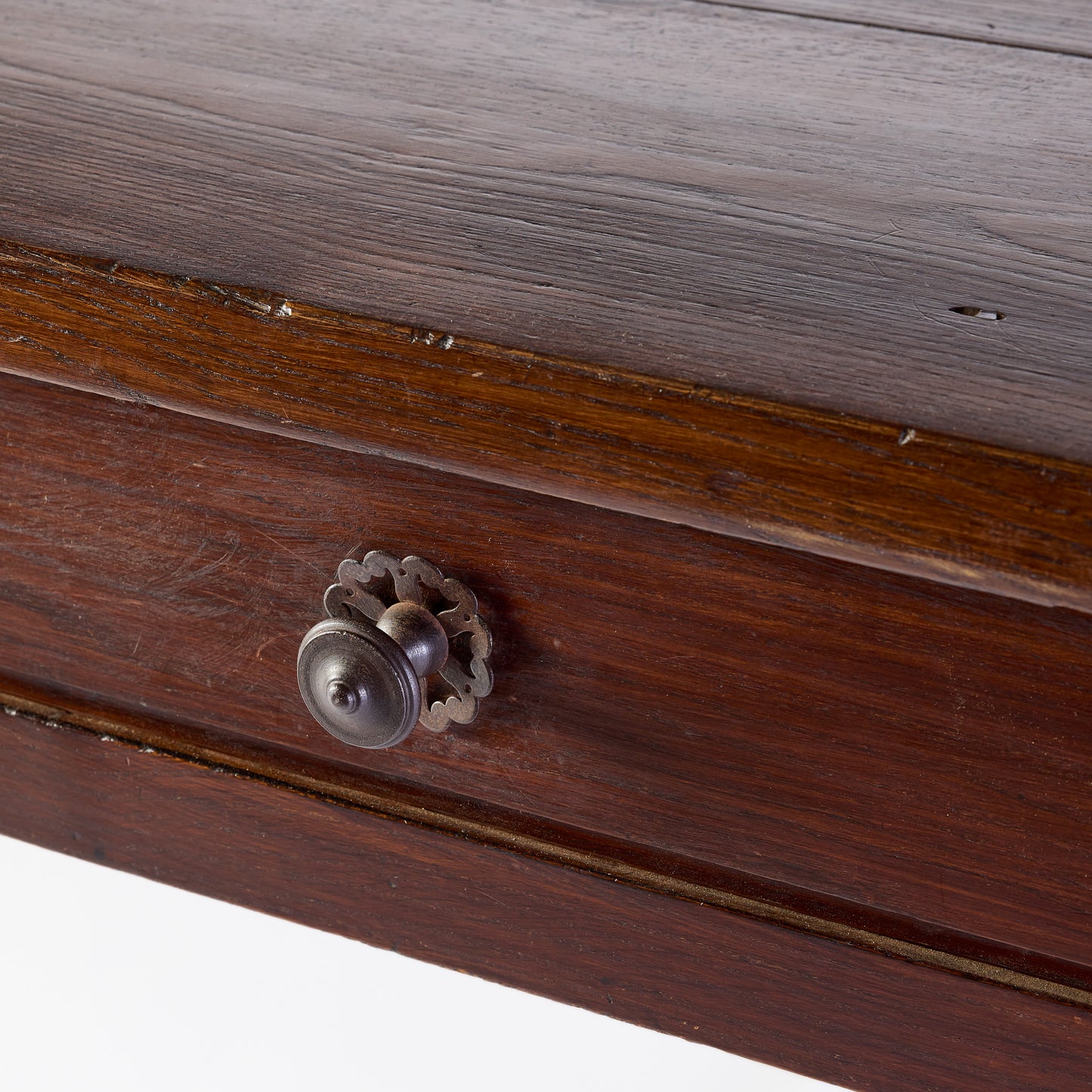 Vintage mahogany kitchen table drawer with a decorative metal knob and aged wood grain finish.