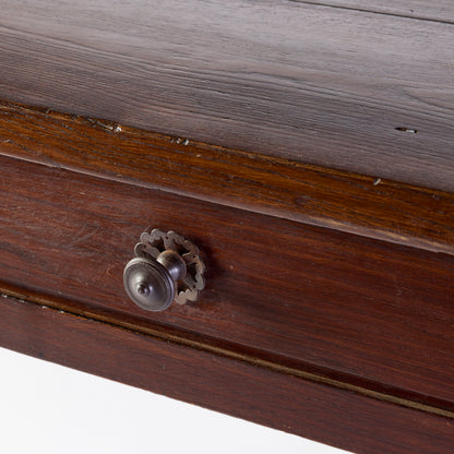 Vintage mahogany kitchen table drawer with a decorative metal knob and aged wood grain finish.