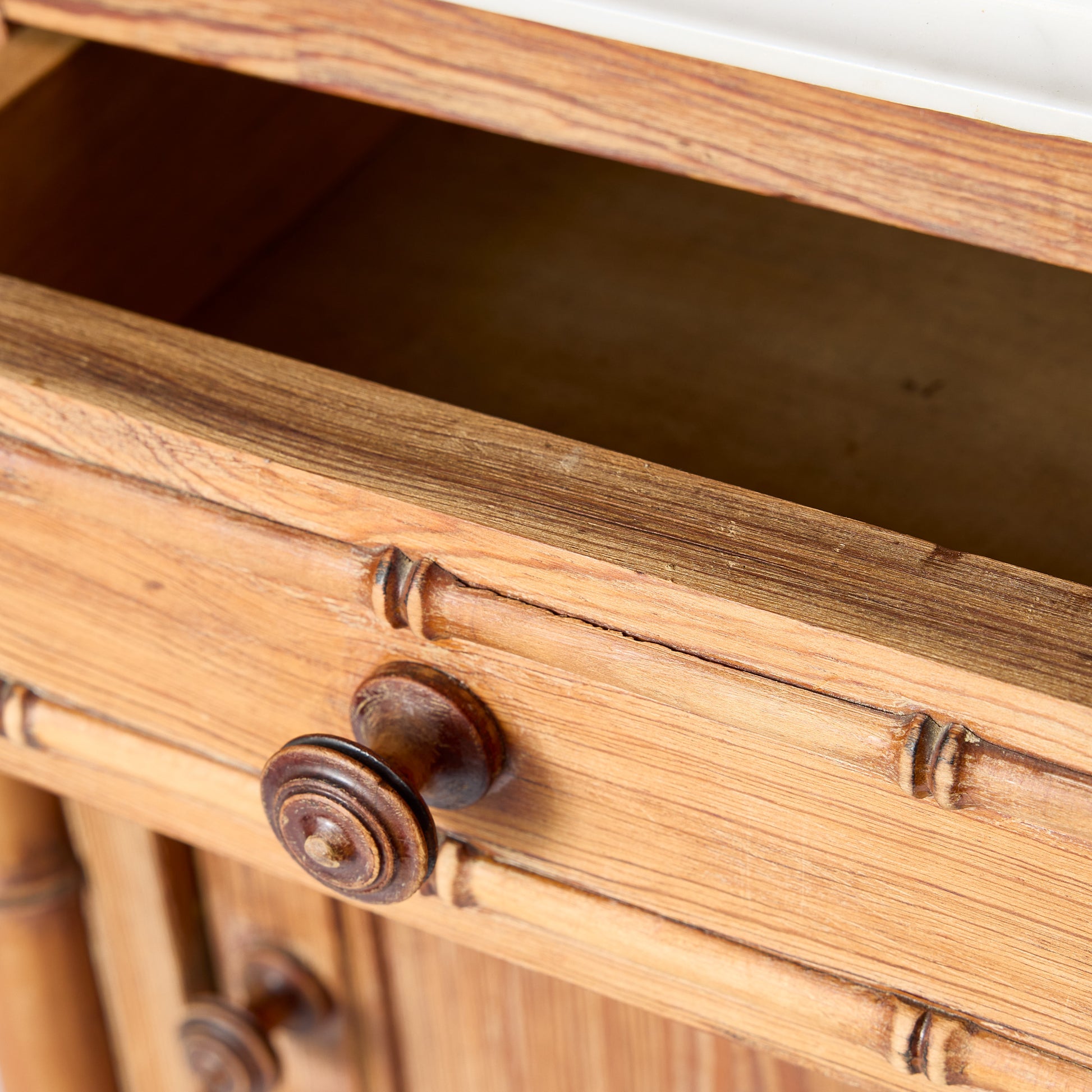 Vintage oak wood nightstand drawer with bamboo-style carving, turned wooden knob, and white marble top.