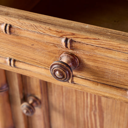 Close-up of a vintage oak wood nightstand drawer with bamboo-style carving and a round wooden knob.