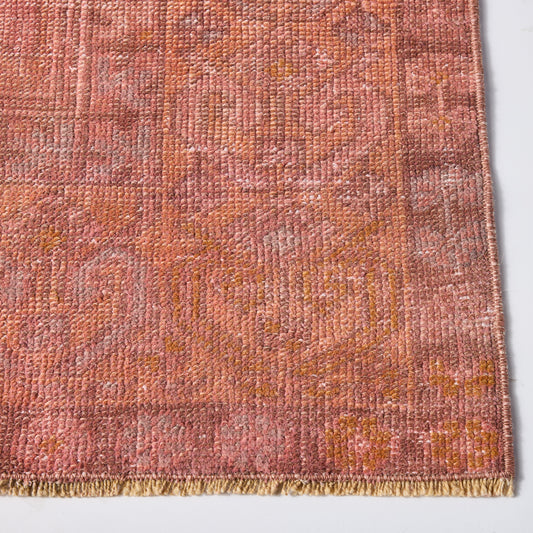 Vintage pink wool rug with a low-pile, faded pattern and fringed edge, measuring 3'10 x 6'1.