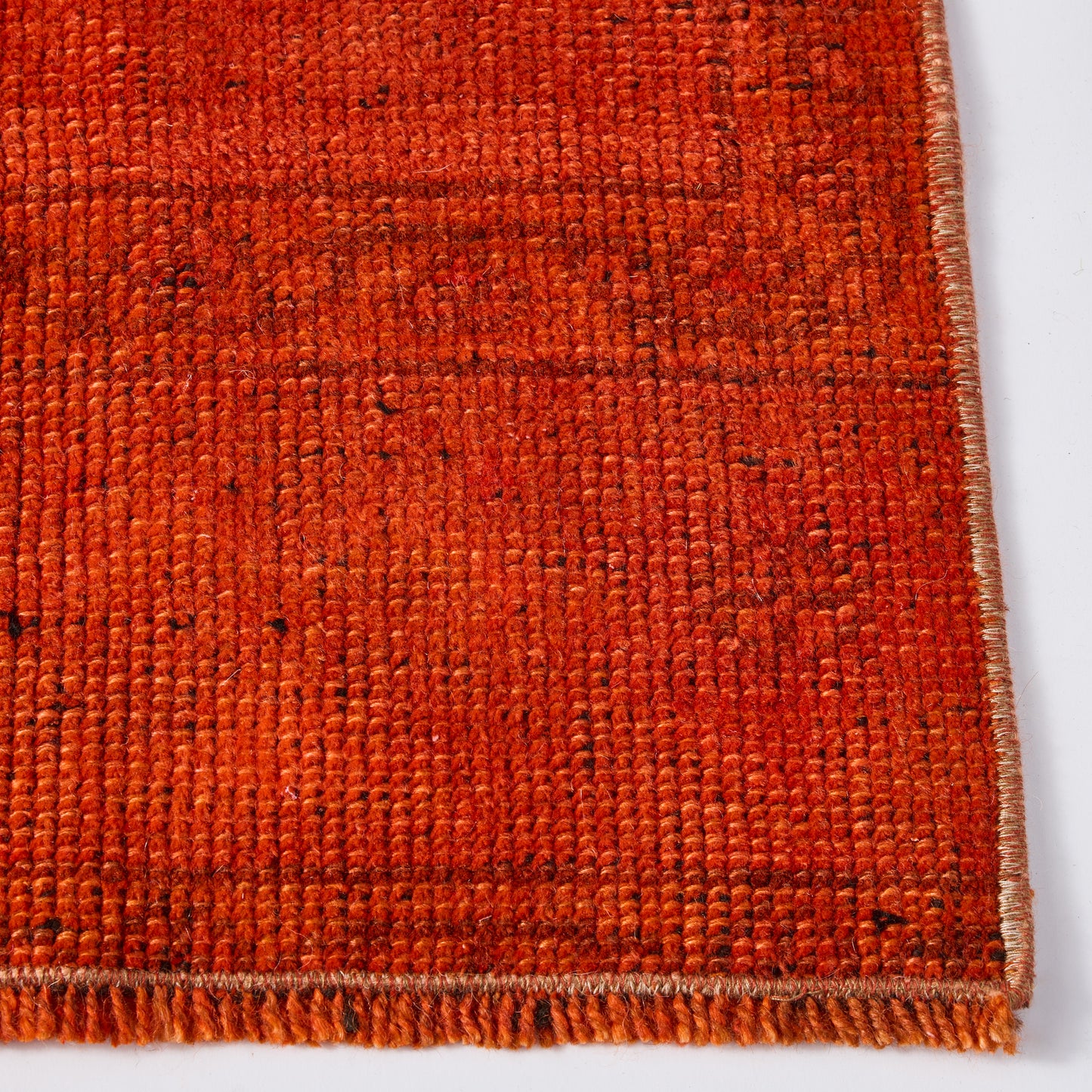 Close-up of a vintage red wool runner rug with a low-pile, handcrafted texture and stitched edge detail.