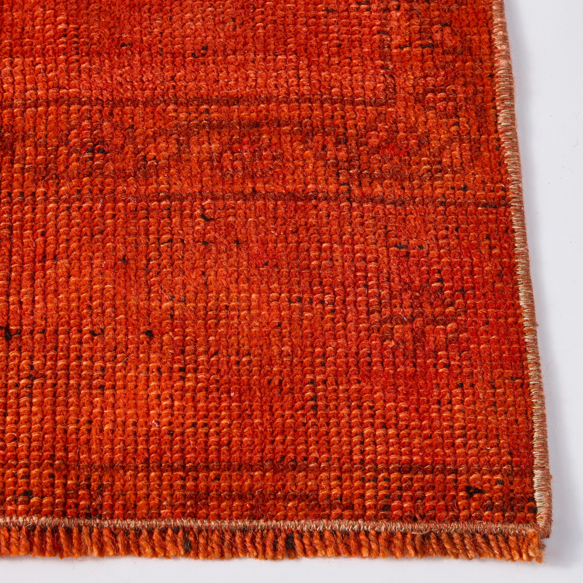 Close-up of a vintage red wool runner rug with a low-pile, handcrafted texture and stitched edge detail.