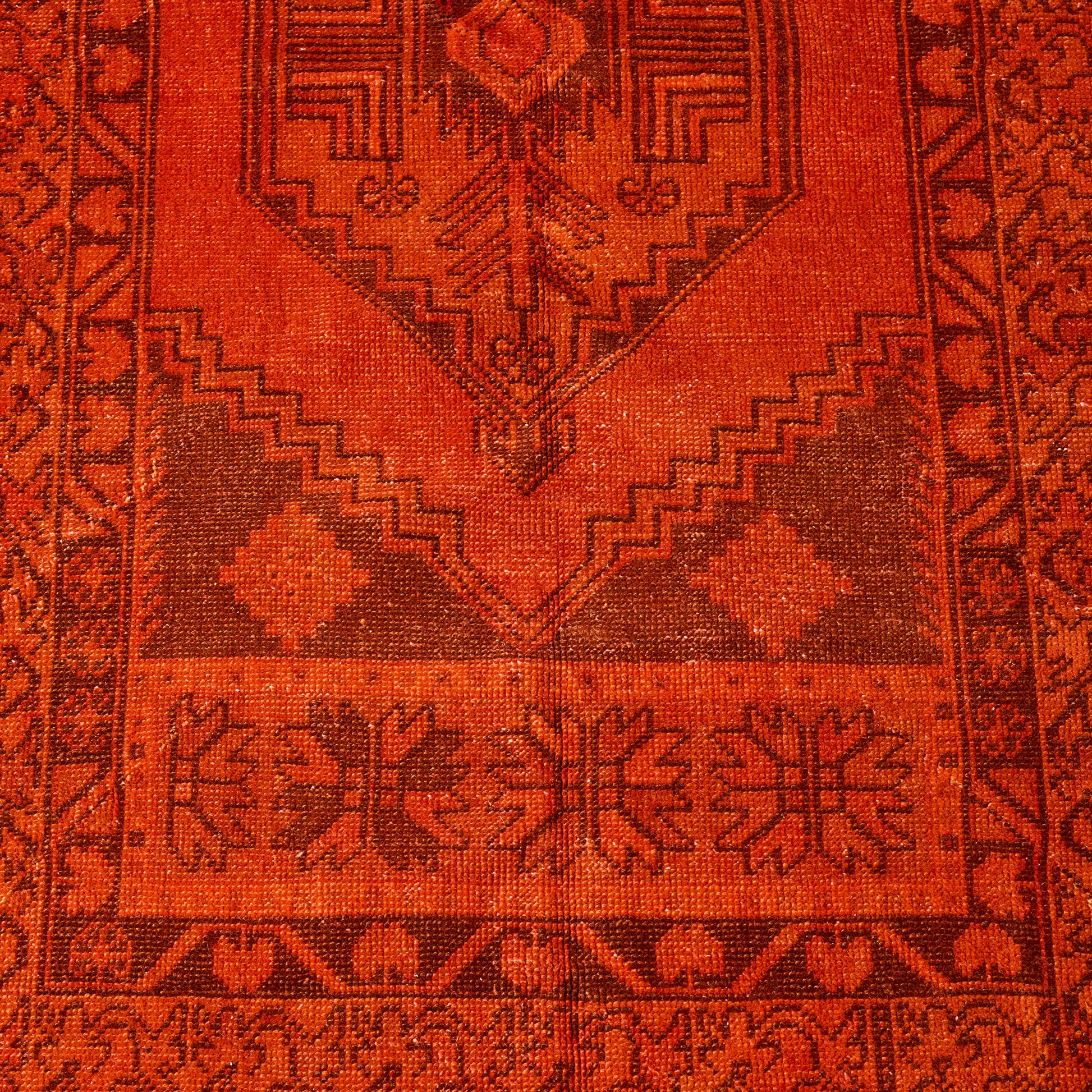 Handcrafted red vintage wool runner rug with faded geometric patterns and low-pile texture.