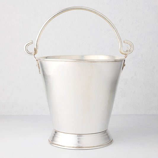 Vintage silverplate champagne bucket with a tapered body, pedestal base, and arched swing handle on a white background.