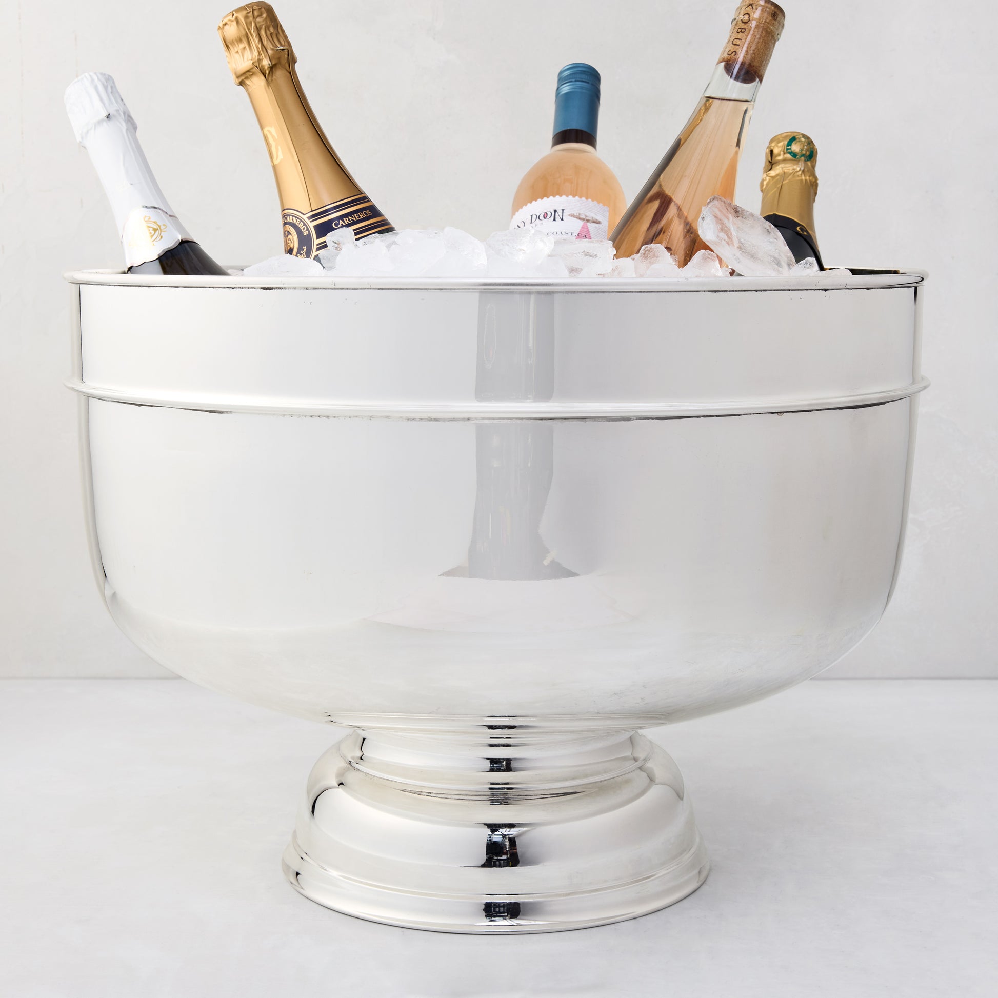 Vintage 18" silverplate footed grand punch bowl, filled with ice and bottles of champagne and wine.