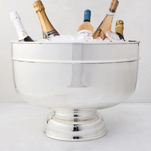 Vintage 18" silverplate footed grand punch bowl, filled with ice and bottles of champagne and wine.