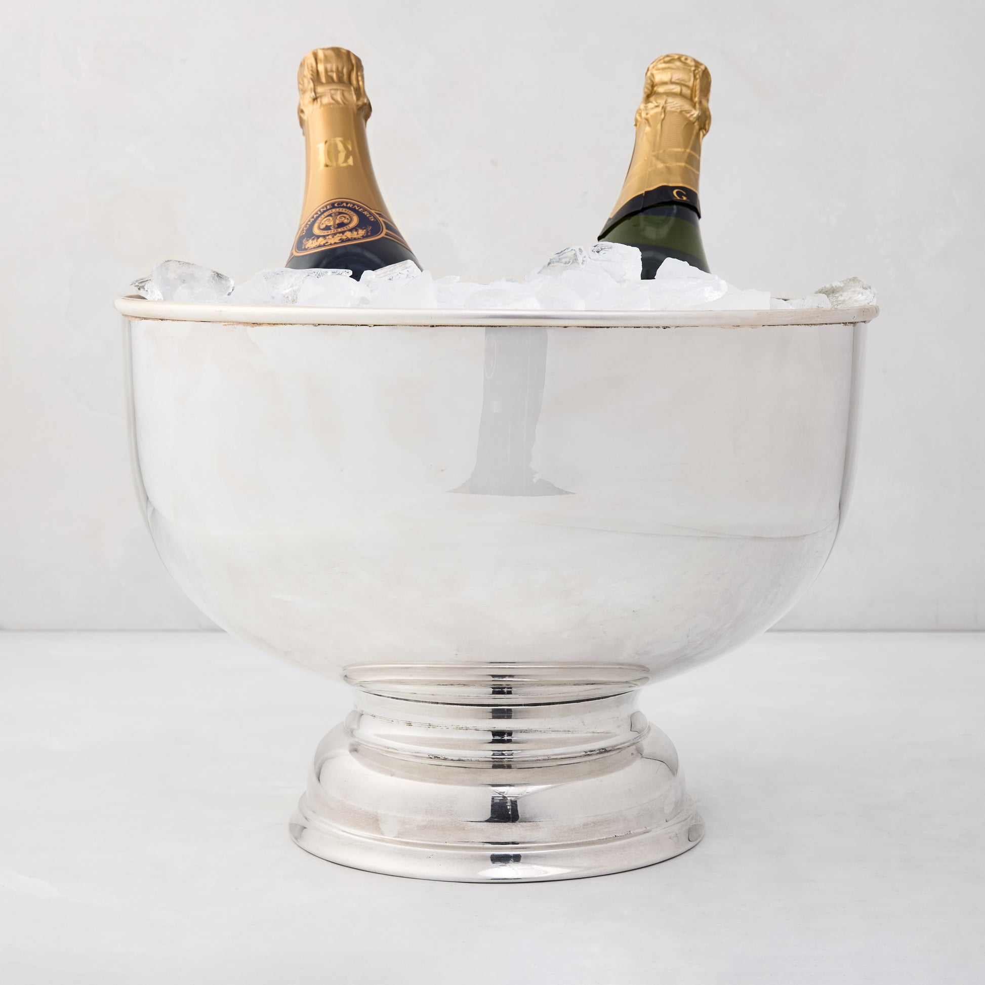 Vintage silverplate footed punch bowl, 12" diameter, holding two champagne bottles on ice.