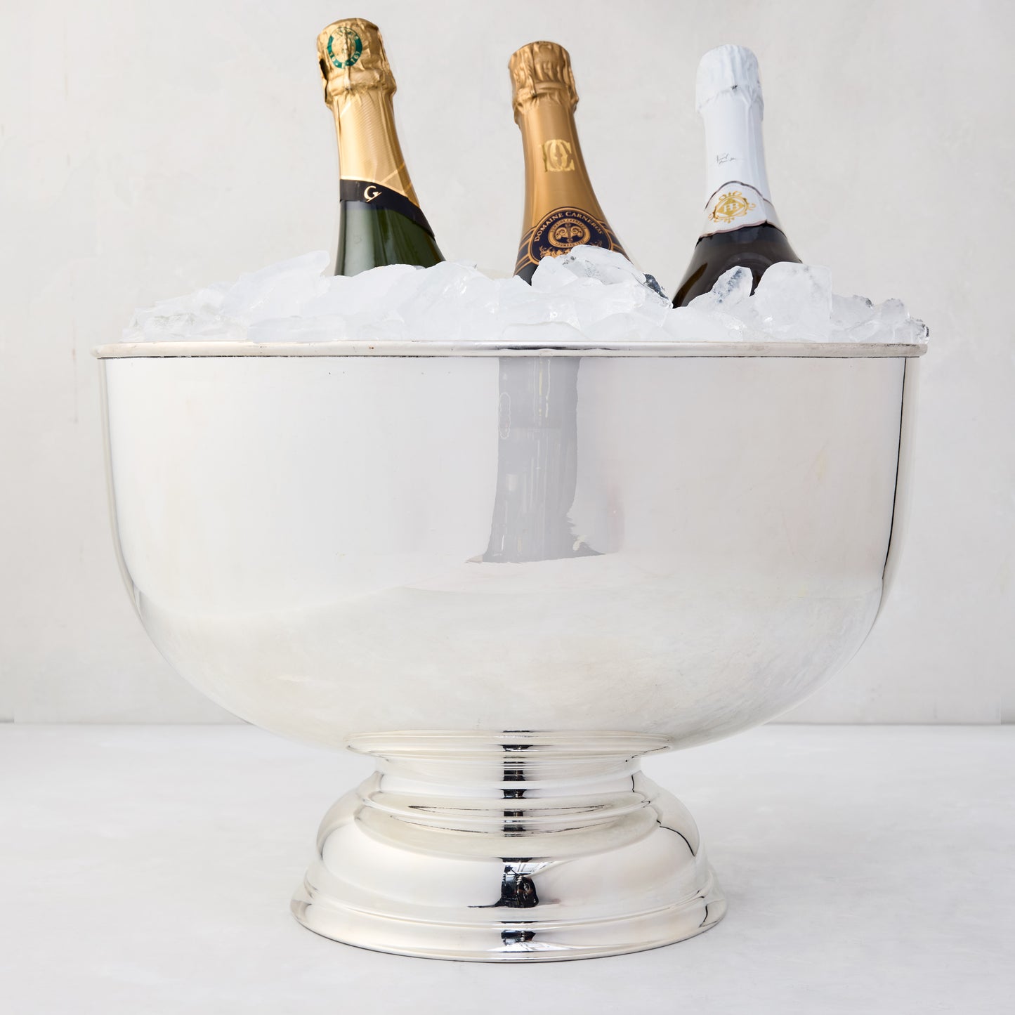 Vintage silverplate footed punch bowl, 14", filled with ice and three champagne bottles.