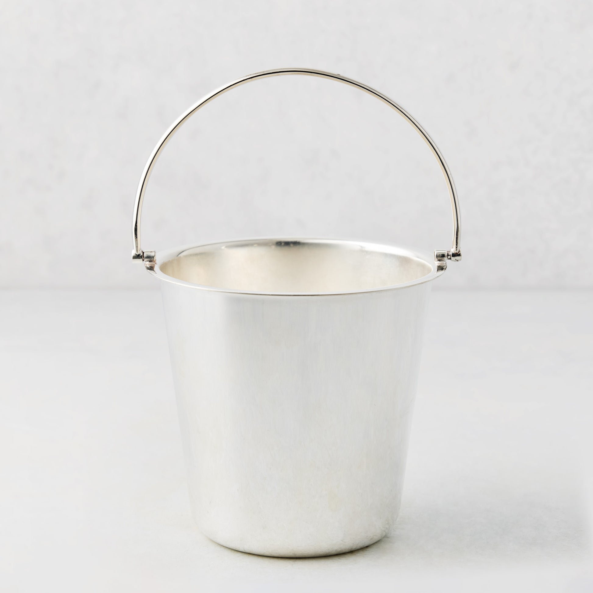 Vintage silverplate Katrina ice bucket with a polished finish and a simple arched handle on a white background.