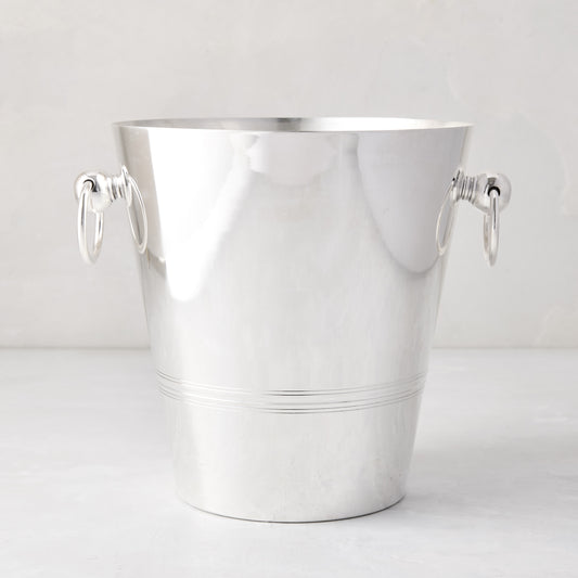 Vintage silverplate champagne bucket with polished finish and decorative side ring handles on a light background.