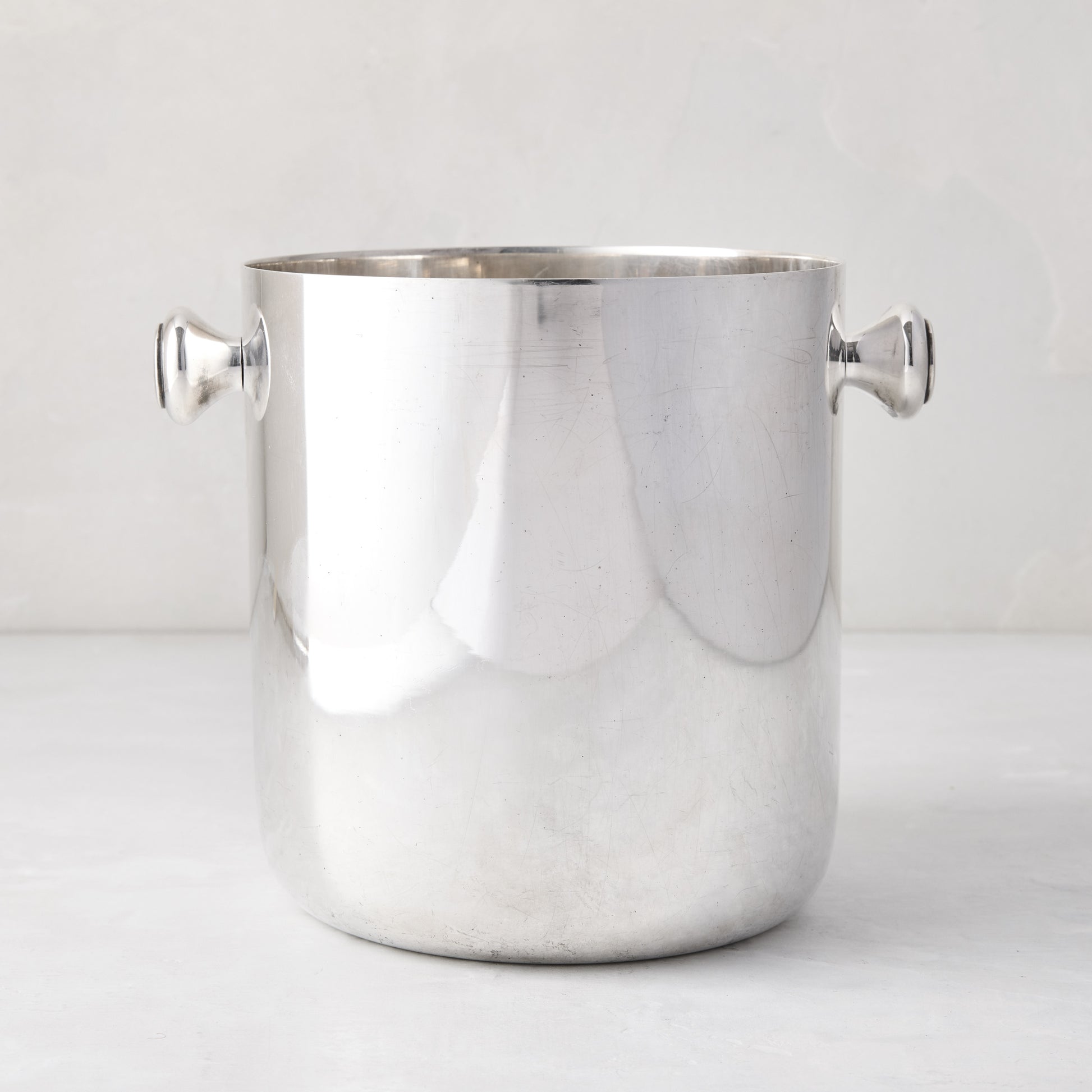 Vintage silverplate champagne bucket with two side handles and a polished finish on a light background.