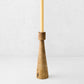 Hand-carved walnut wood candlestick with a geometric tapered base and a cream taper candle on a white background.