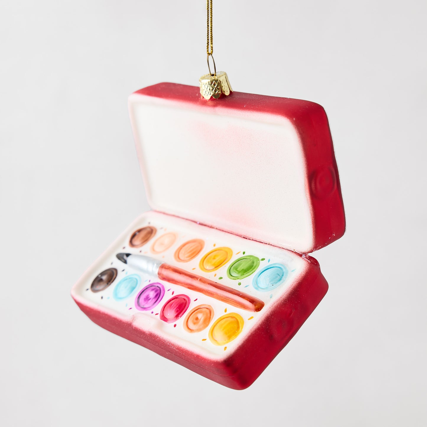 Hand-painted glass and resin watercolor paint set ornament with a red case, colorful paint wells, and a brush.