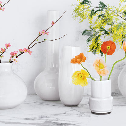 Oversized opaque white handblown glass Bucca vase with pink, orange, and yellow flowers.