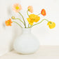 Oversized opaque white handblown glass Bucca vase with colorful poppies.