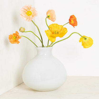 Oversized opaque white handblown glass Bucca vase with colorful poppies.