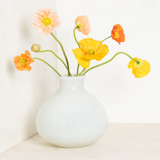 Oversized opaque white handblown glass Bucca vase with colorful poppies.
