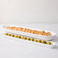 White ceramic baguette and olive serving tray set with sliced bread and green olives.