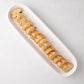 White ceramic narrow oval baguette serving tray with sliced bread.