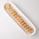 White ceramic narrow oval baguette serving tray with sliced bread.
