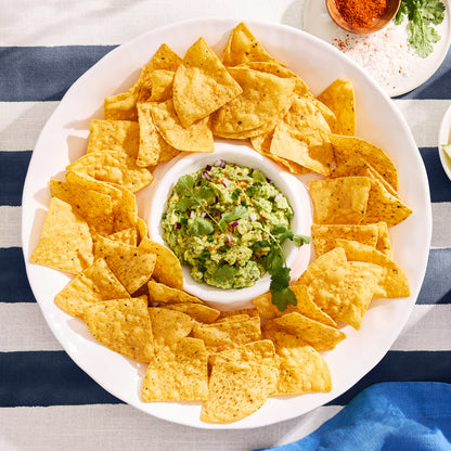 White ceramic 15"Dia chip and dip platter with a ruffled edge, filled with tortilla chips and guacamole.