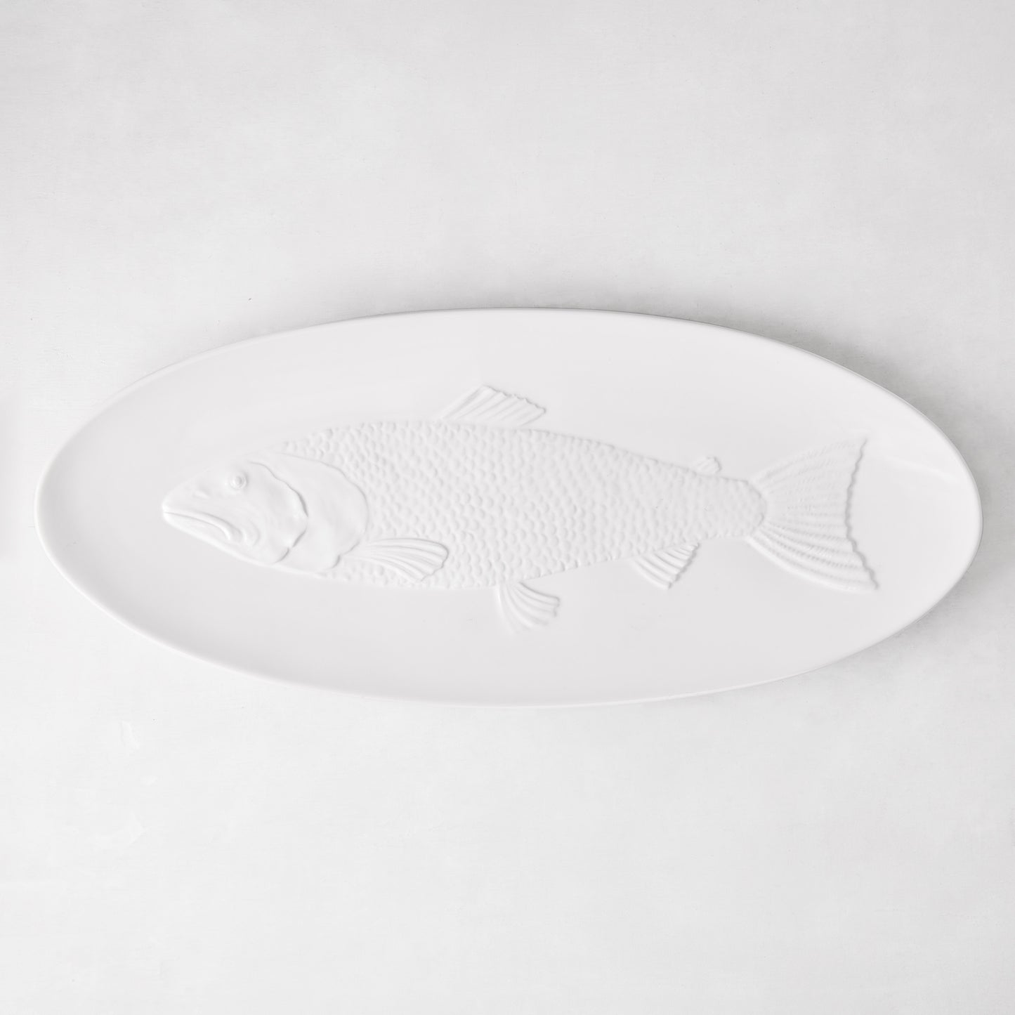 White ceramic oval serving platter with an embossed fish design.