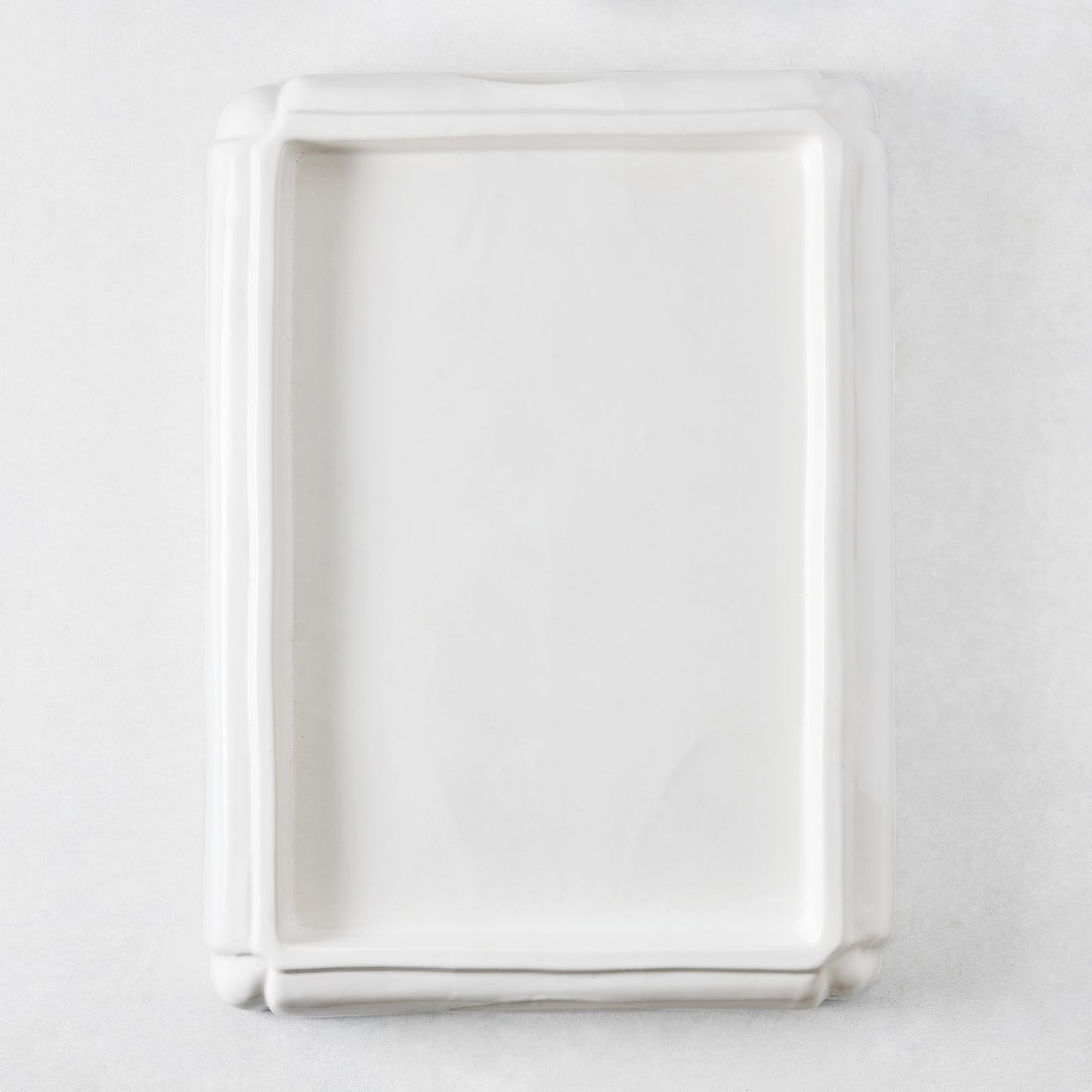 Rectangular white ceramic serving tray with a raised rim and decorative molded edges on a white background.
