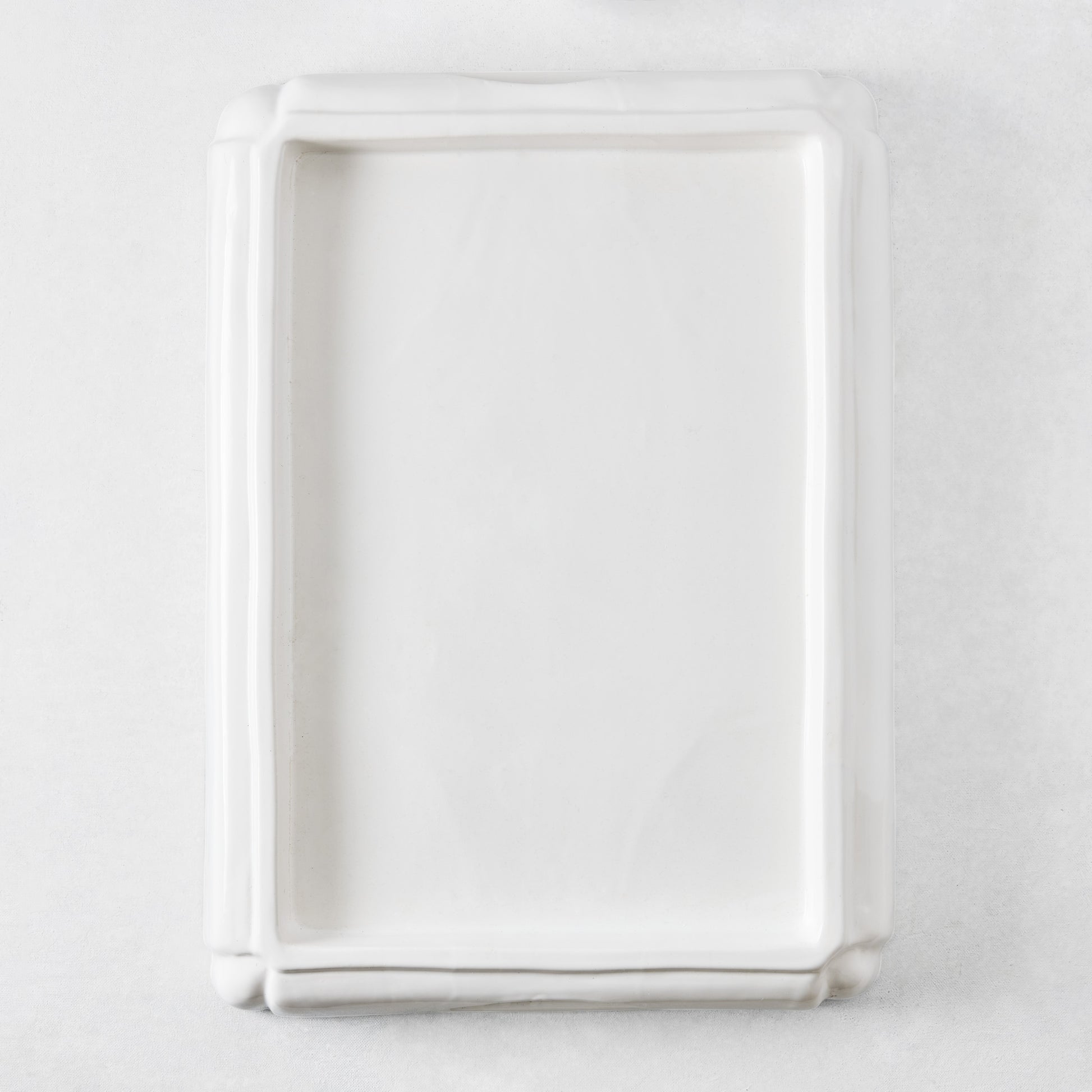 Rectangular white ceramic serving tray with a raised rim and decorative molded edges on a white background.