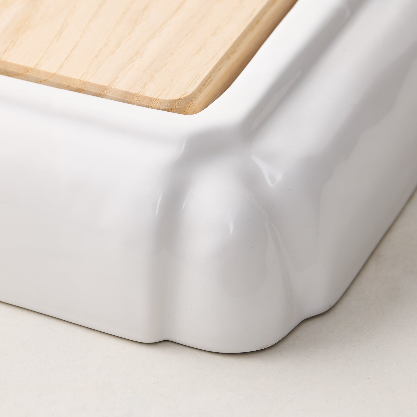 White ceramic handled cutting board with light oak wood surface.