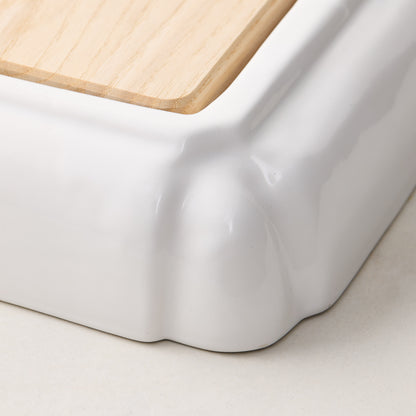 White ceramic handled cutting board with light oak wood surface.