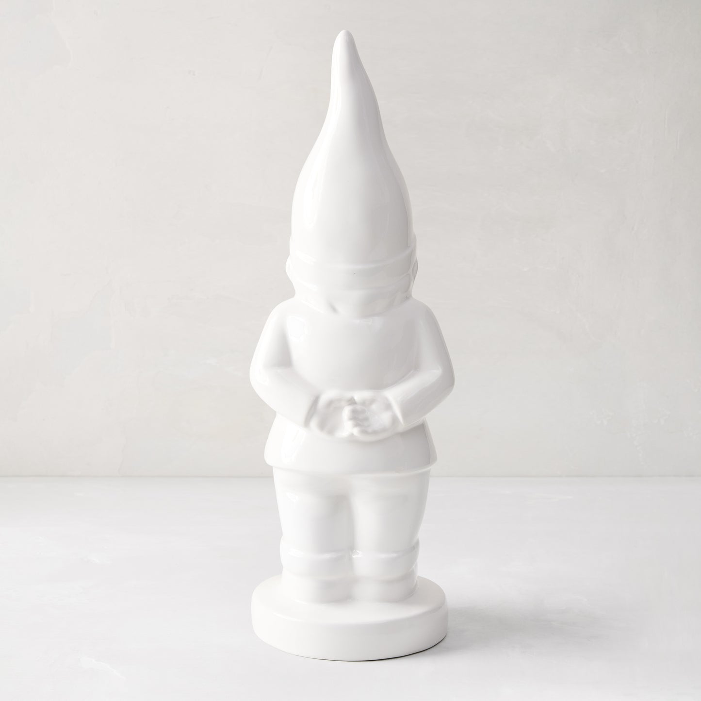 White ceramic holiday gnome with a tall, pointed hat and creamy white glaze.