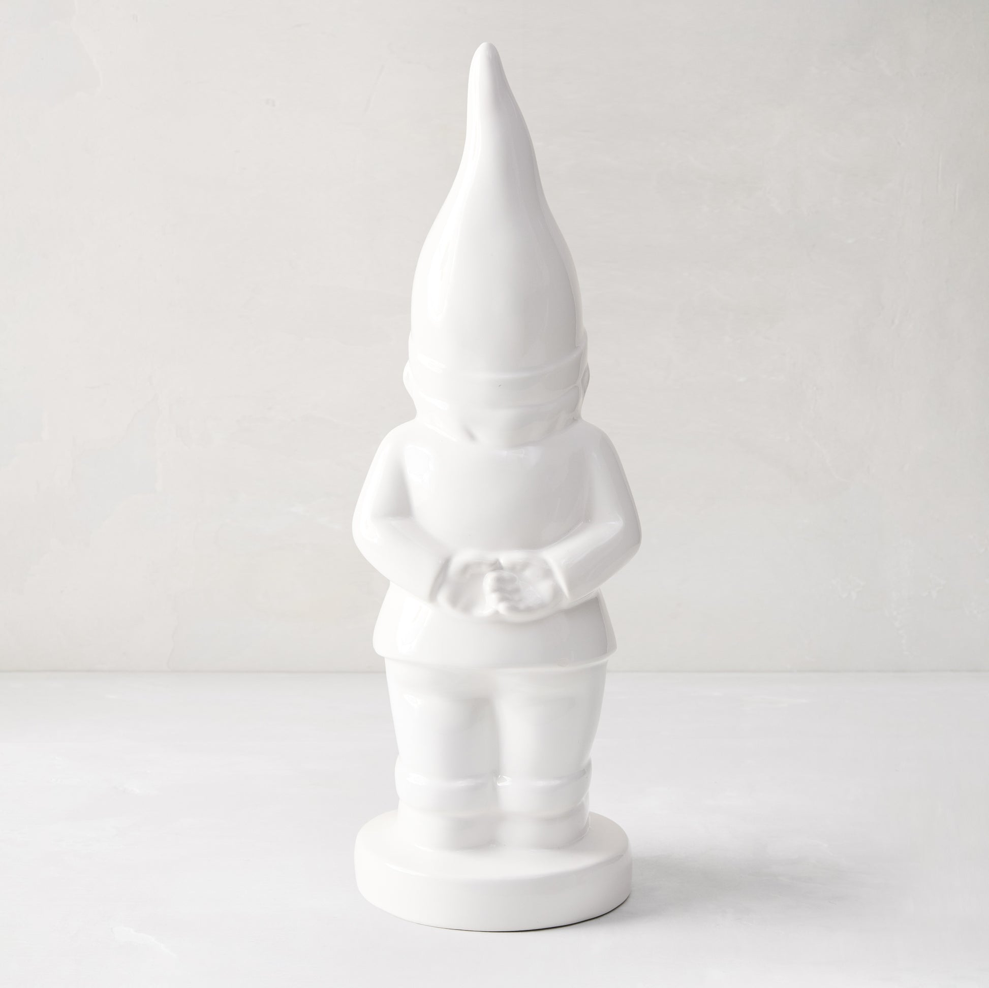 White ceramic holiday gnome with a tall, pointed hat and creamy white glaze.
