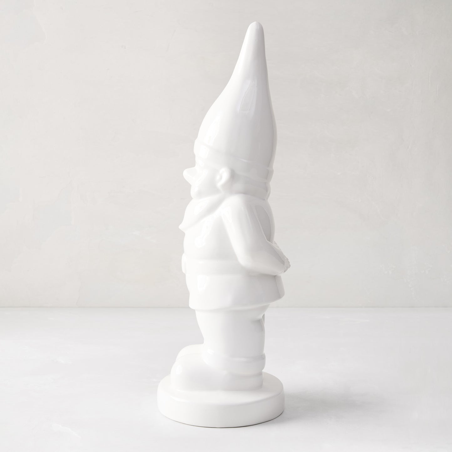 White ceramic holiday gnome with a tall, pointed hat and creamy white glaze.
