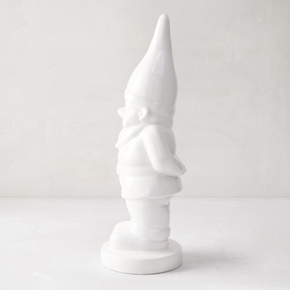 White ceramic holiday gnome with a tall, pointed hat and creamy white glaze.