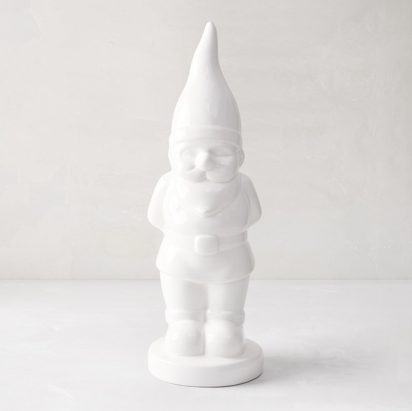 White ceramic holiday gnome with a tall, pointed hat and creamy white glaze.