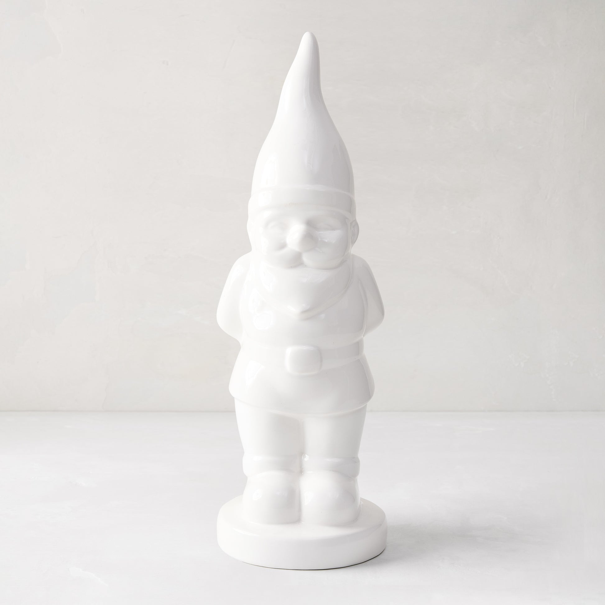 White ceramic holiday gnome with a tall, pointed hat and creamy white glaze.