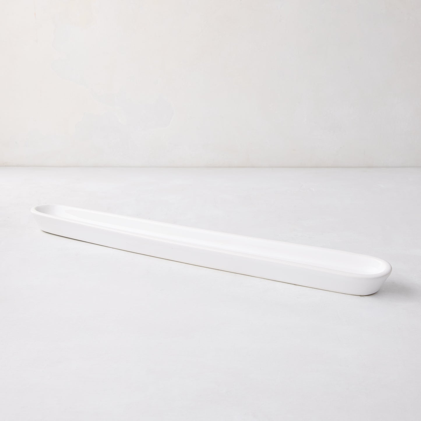 White ceramic olive serving tray, 16" long, with a narrow, rectangular shape and rounded ends.