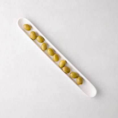 White ceramic olive serving tray, 16" long, filled with green olives.
