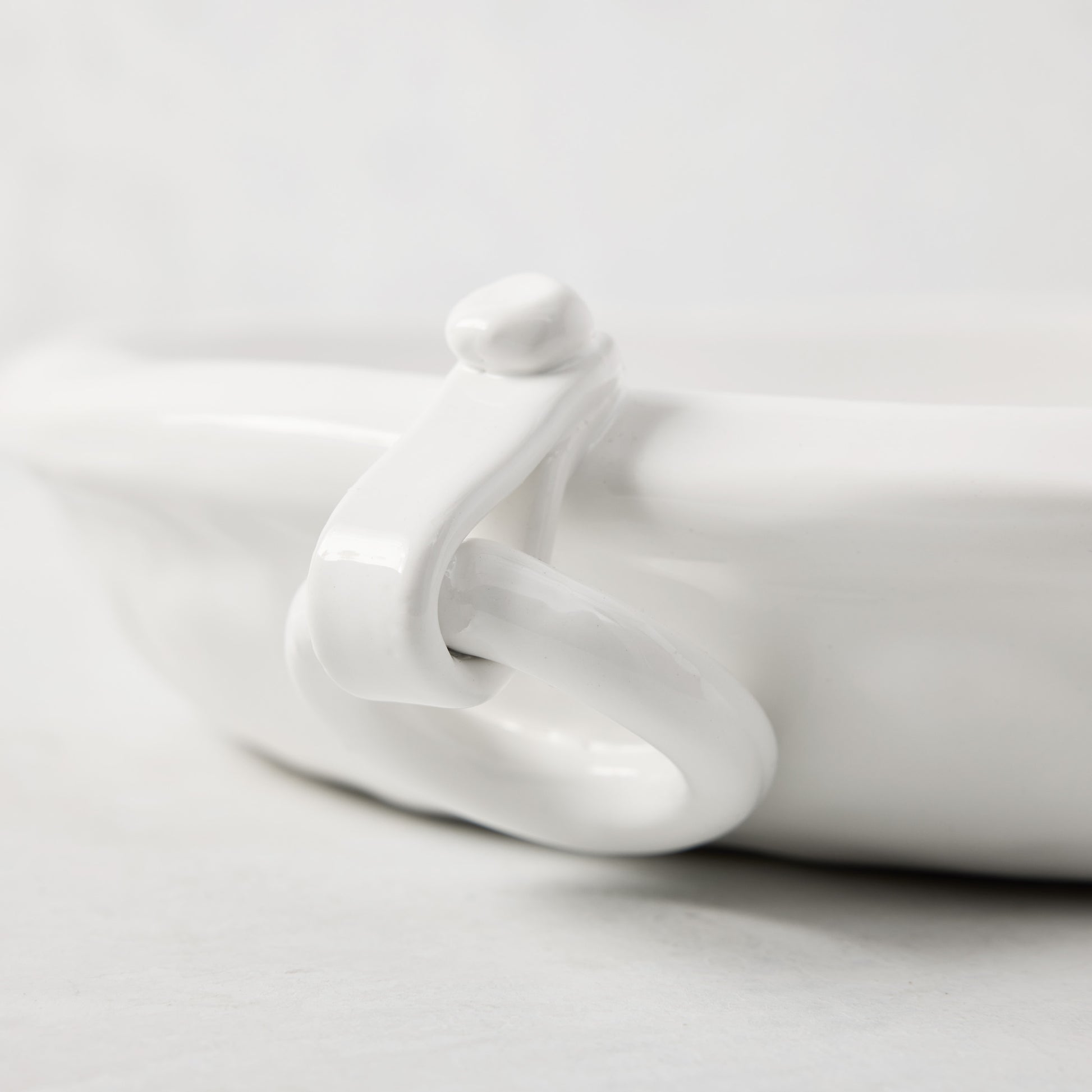 White ceramic oval platter with a ring handle and faux strap detail.