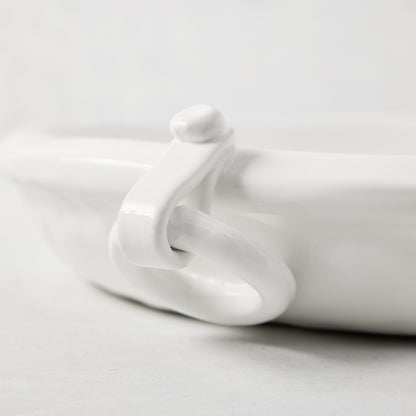 White ceramic oval platter with a ring handle and faux strap detail.