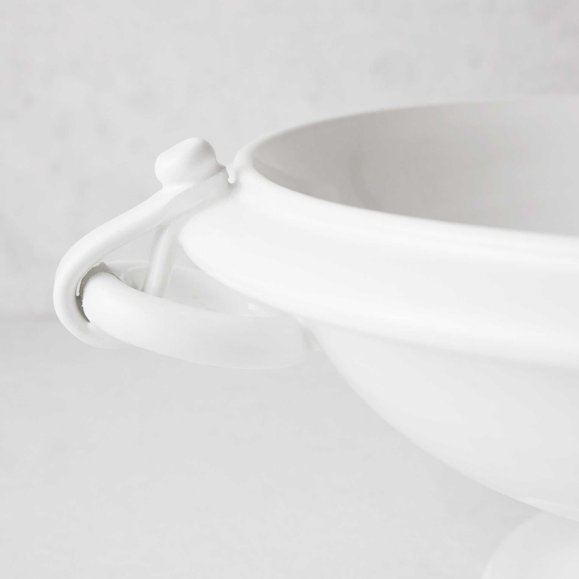 White ceramic pedestal fruit bowl with ring handle and faux straps.